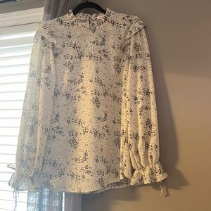 Cream blouse with black speckle pattern.
